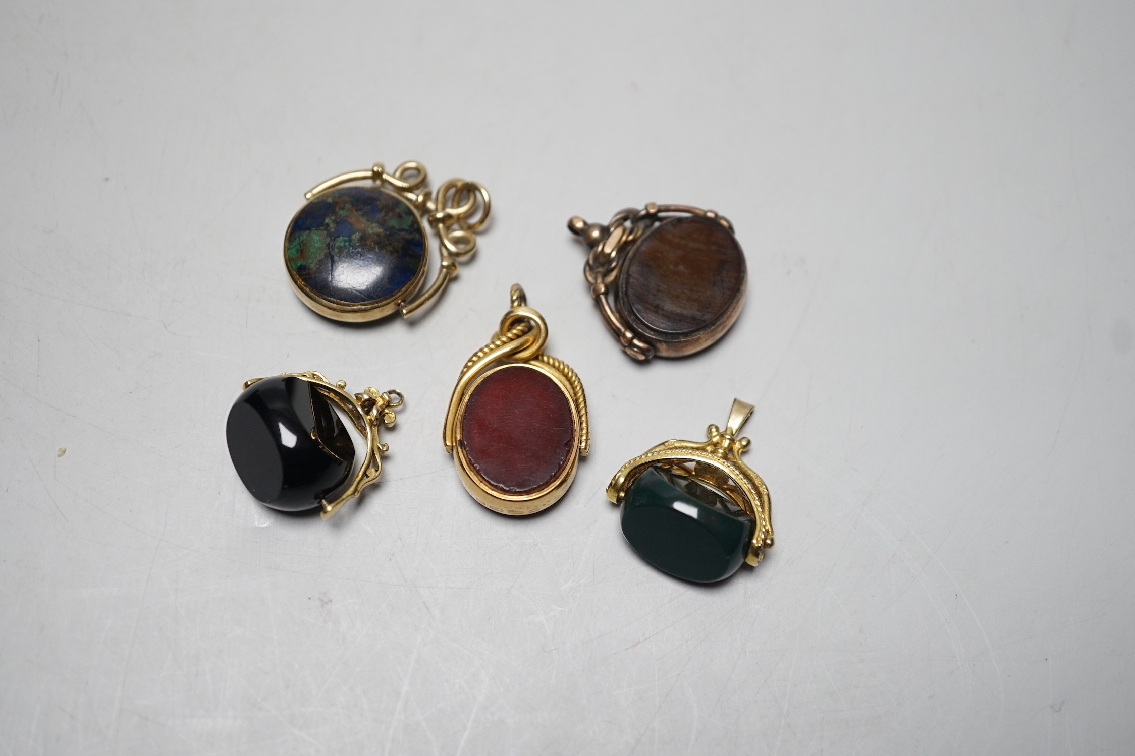 A late Victorian 18ct gold mounted bloodstone and carnelian set spinning fob seal, 36mm, a similar 9ct seal, a yellow metal and turquoise set fob seal and two later 9ct gold mounted seals.